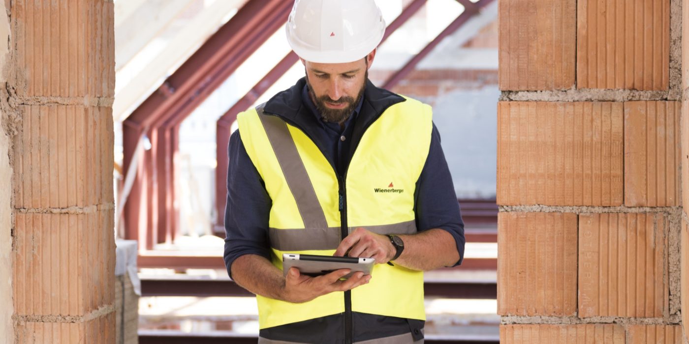 Product manager standing in attic under renovation checking tablet