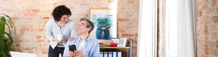 Man with phone in conversatuion with woman in front of brick-lined wall