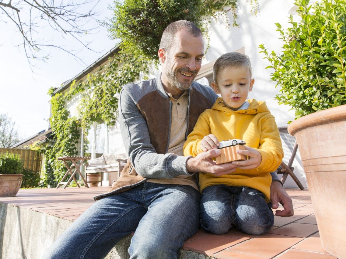 Adult man plays with young boy on patio