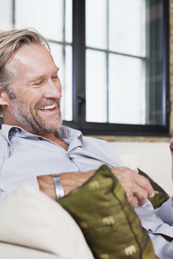 Man with miniature brick sitting on sofa in front of brick wall