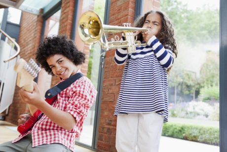 Noisy kids playing electrical guitar and trumpet inside well insulated brick-built house