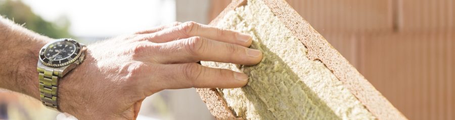 Hand touching mineral wool of internal insulation filled clay block