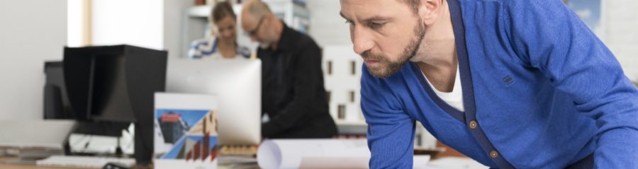 Architect at office studying blueprint holding tablet