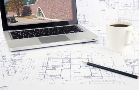 Working space with reference picture on laptop and architecture plan on desk