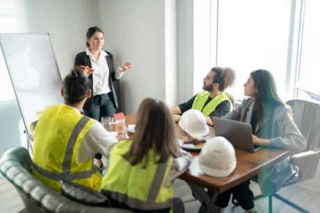 Businesswoman is talking about new project in the meeting room. Her team is sitting around a table and listening their manager carrefully.
